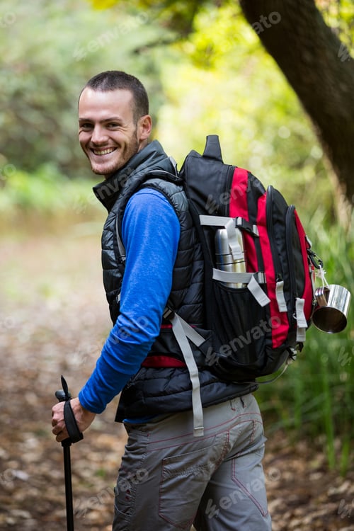 Preview: Portrait Of Smiling Male Hiker Walking With Hiking Pole In Forest