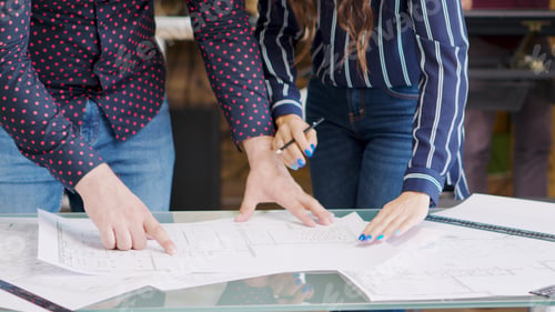 Preview: Professional architects drawing over blue prints on the table