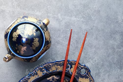 Preview: Empty plate, teapot with herbal tea and chopsticks over table