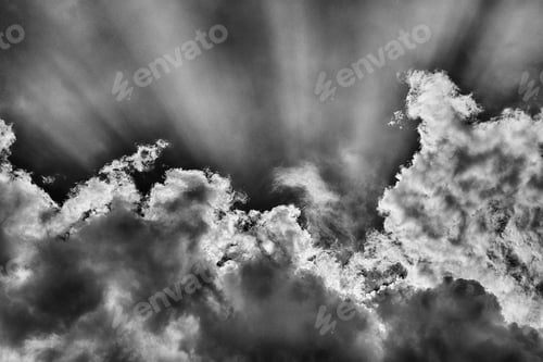 Preview: Low angle shot of the sun shining behind the clouds in black and white