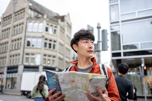 Preview: Asian young man backpacker traveler looking at map to find destination.