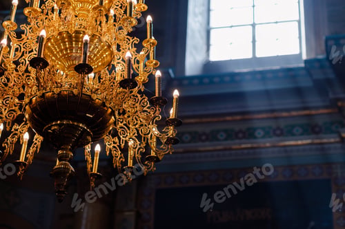 Preview: Big bronze chandelier with electric candles in cathedral christian church. daylight from the window