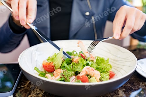 Preview: Close up Young woman eating seafood salad in cafe outside