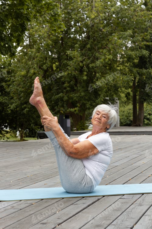 Preview: an old, elderly woman of 85 years old does a v-up exercise, a yoga exercise.Health, activity
