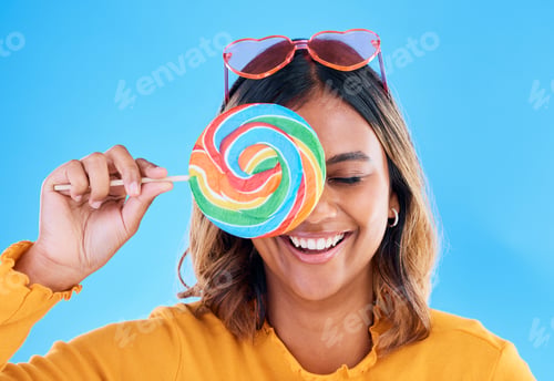 Preview: Laughing, lollipop and a woman on a blue background in studio wearing heart glasses for fashion. Fu
