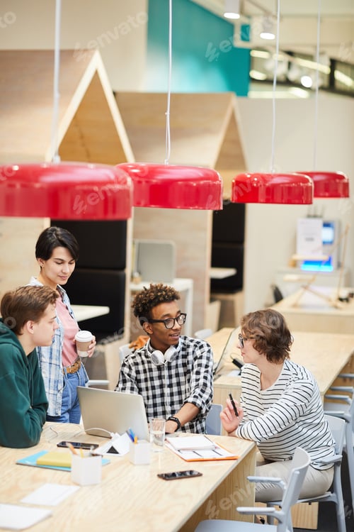 Preview: Multiethnic students discussing university project in cafe