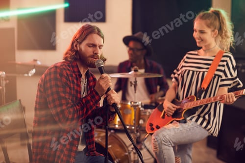 Preview: Bearded Young Man Singing to Microphone with Band in Studio