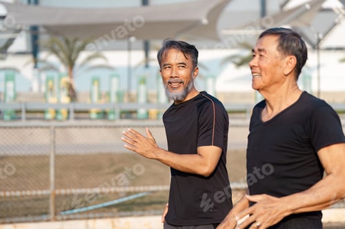 Preview: Joyful senior Asian men jogging together on a sports field, promoting wellness and active living.