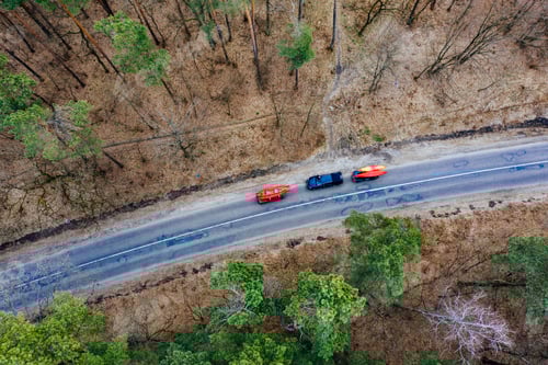 Preview: Several cars with kayaks on roof rack driving on the road among trees
