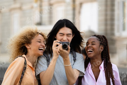 Preview: Front view of multiethnic young tourists enjoy their visit to a city taking photos