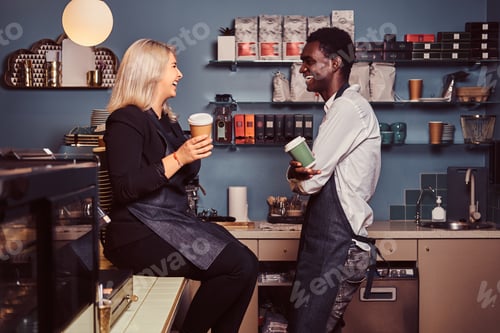 Preview: Two young multiracial baristas relaxing after work at the trendy coffee shop