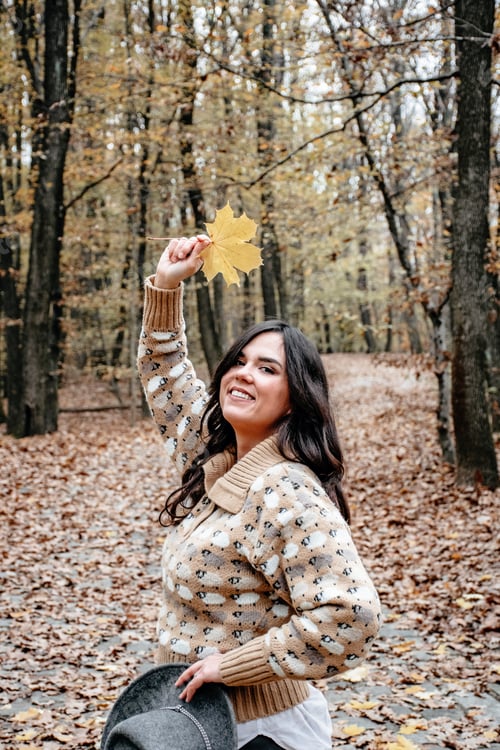 Preview: Shot of a beautiful woman in autumn forest with a maple leaf on the hand
