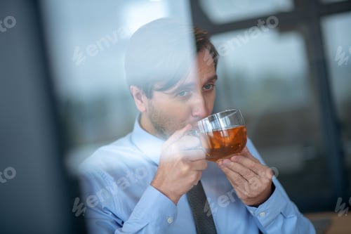 Preview: Blue-eyed businessman drinking hot tea at work