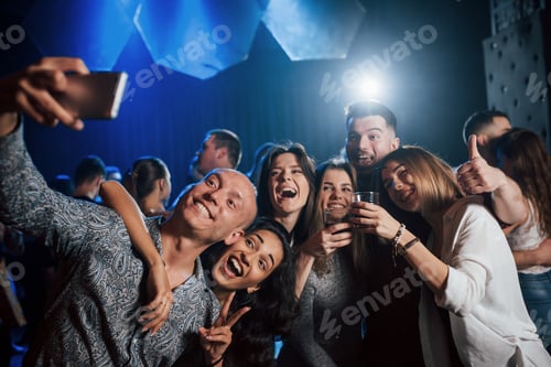 Visualização: Polegar e álcool para cima. Amigos tirando selfie em uma linda boate. Com bebidas nas mãos