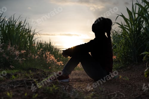 Preview: Farmer woman silhouette sitting in the sugar cane plantation in the background sunset evening