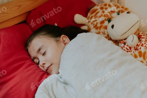 Preview: A little girl sleeps in bed with a giraffe toy.
