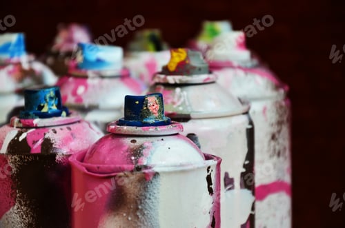 Preview: Still life with a large number of used colorful spray cans of aerosol paint lying on the treated