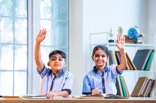 Preview: Indian Students in school uniforms raise hands to answer teacher’s question during classroom session