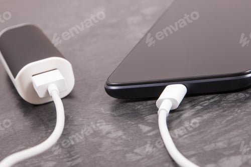 Preview: Black smartphone with connected plug of external powerbank. Mobile phone charging
