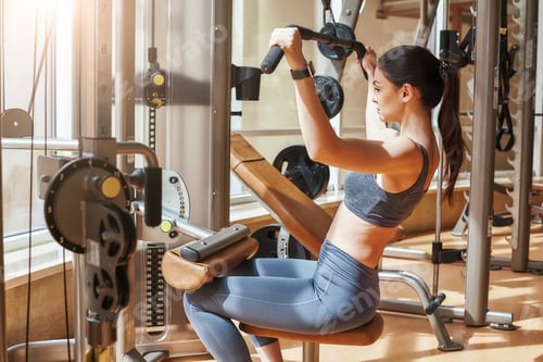Preview: Way to perfection. Side view of sporty young woman doing body exercise for chest at gym