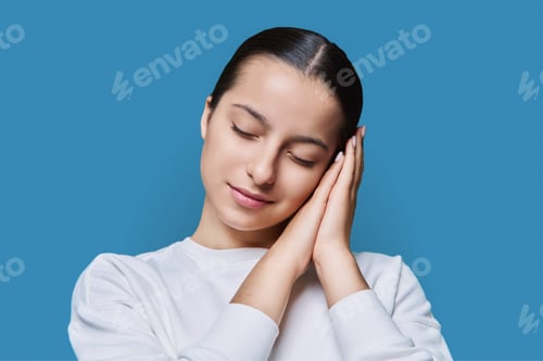 Preview: Young woman sleeping with closed eyes, on blue studio background