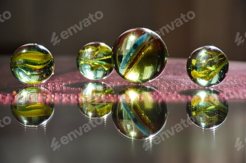 Preview: Colorful children's glass marbles on a reflective glass surface