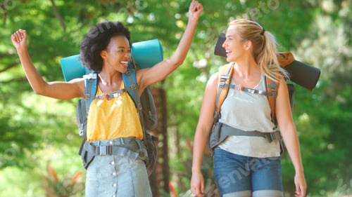 Preview: Two Female Friends With Backpacks Setting Off On Vacation Hiking Through Countryside Together