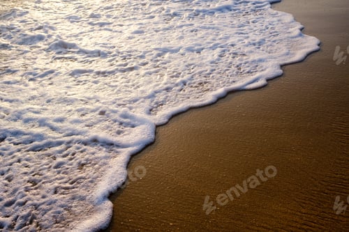 Preview: Gentle waves wash over golden sand during sunset on a tranquil beach in a coastal location