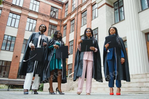 Preview: young graduates standing in front of university building on graduation day