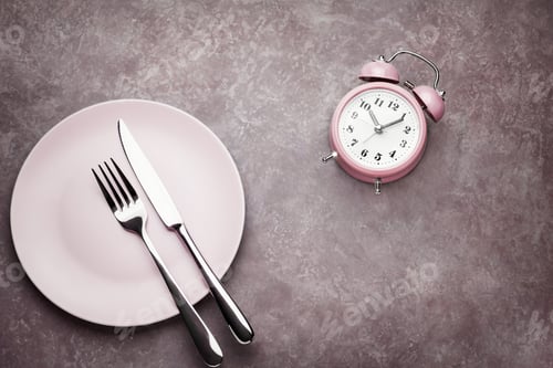 Preview: Alarm clock and plate with cutlery. Concept of intermittent fasting, lunchtime, diet and weight loss