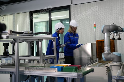Preview: Female technician programs a robot arm with a digital tablet and assembly robot in a factory