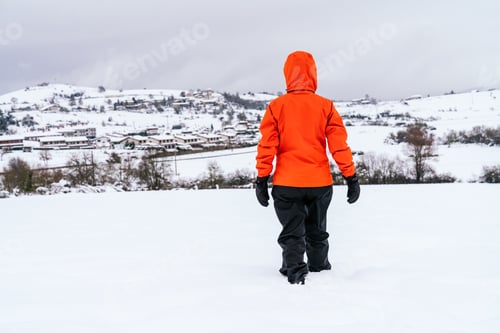 Preview: back view of a woman walking in the snow on a mountain with a beautiful landscape