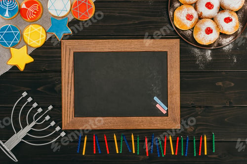 Preview: top view of frame, menorah, donuts and cookies with star of david on wooden tabletop, hanukkah