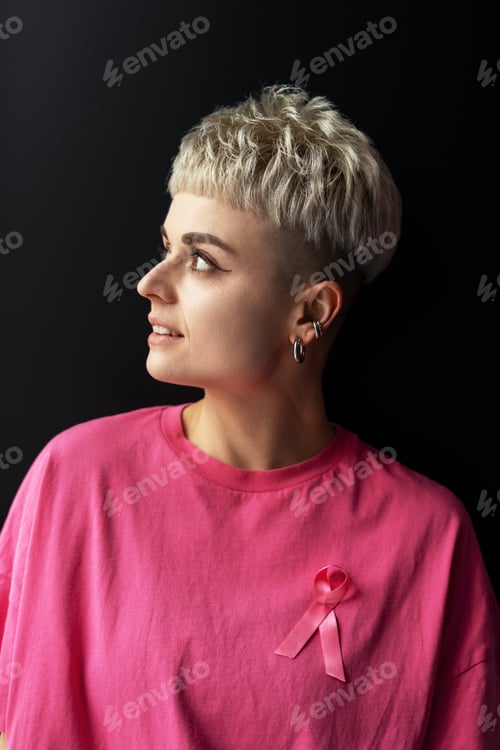 Preview: Young woman wearing pink ribbon looking aside against black background
