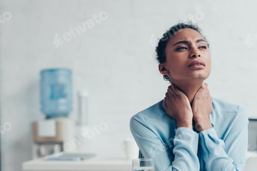Preview: pretty african american businesswoman suffering from neck pain in office