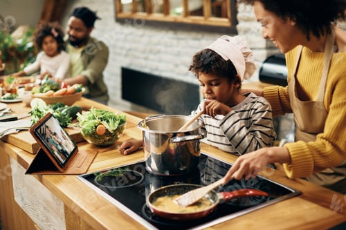 Preview: African American son assisting mother in preparing food in the kitchen.