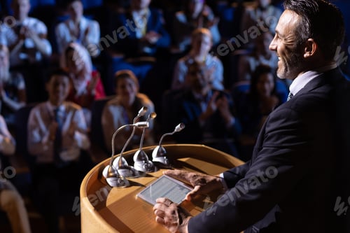 Preview: Side view of Caucasian businessman standing and giving presentation in the auditorium