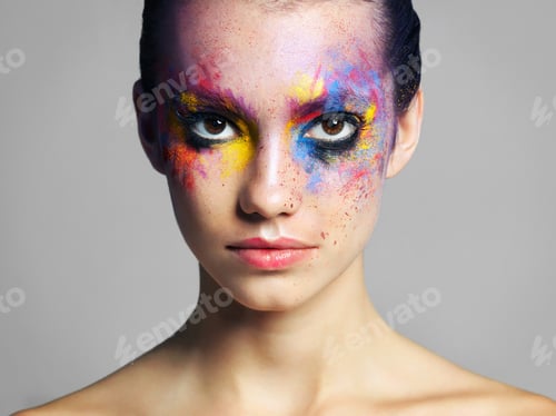 Vista previa: Fotografía de estudio de una atractiva joven con maquillaje de colores brillantes sobre un fondo gris