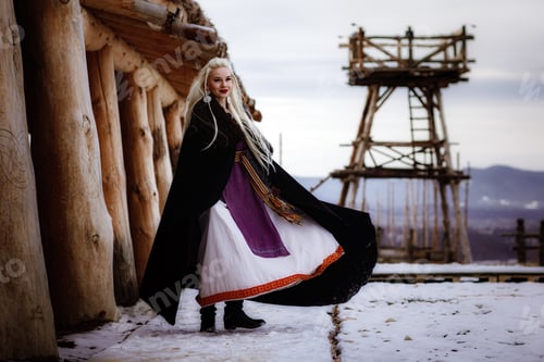 Preview: Beautiful blonde Viking dressed in a black cloak against the backdrop of the castle