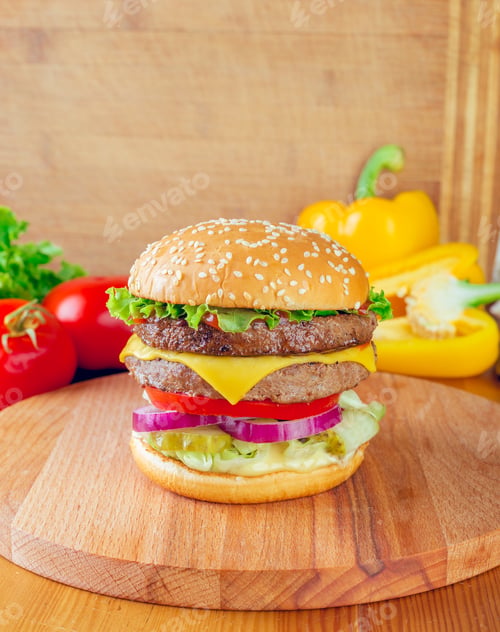 Preview: Juicy double cheeseburger with fresh vegetables on wooden board surrounded by colorful peppers and