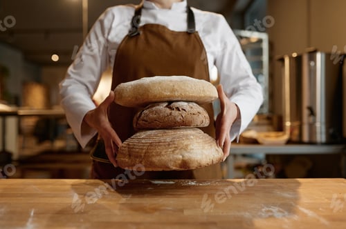 Preview: A baker holding stack of freshly baked bread