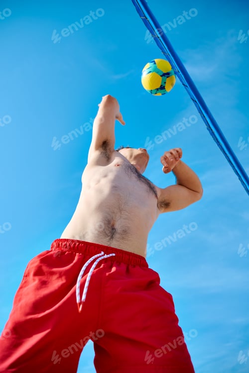 Preview: Beach volleyball player serving under blue sky