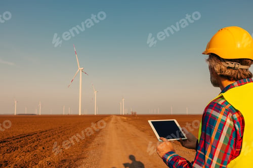 Preview: Engineer checking wind turbines at field and using technology