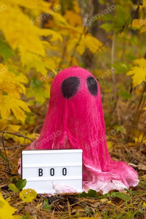 Preview: Creative handmade Halloween holiday decoration. pink ghost with Lightbox BOO text in autumn leaves