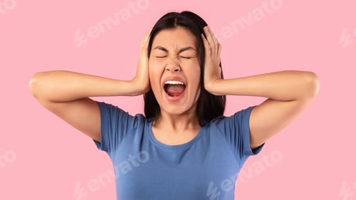 Preview: Angry asian woman covering her ears with hands and screaming