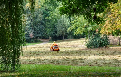 Preview: Man riding on a lawnmower tractor in a park
