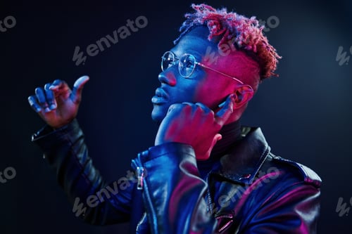 Preview: Listening to the music. Futuristic neon lighting. Young african american man in the studio