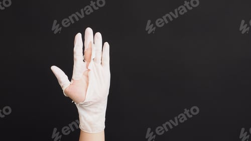Preview: Hand Wearing torn latex glove or torn rubber gloves on black background.