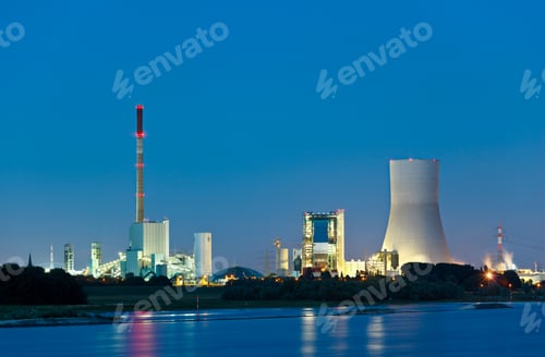 Preview: Illuminated Industrial Complex Along River at Night