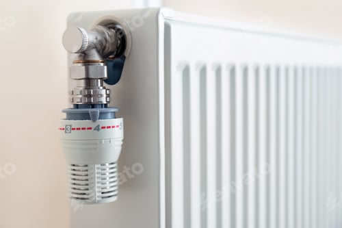 Preview: Heating radiator with thermostat near light wall, closeup